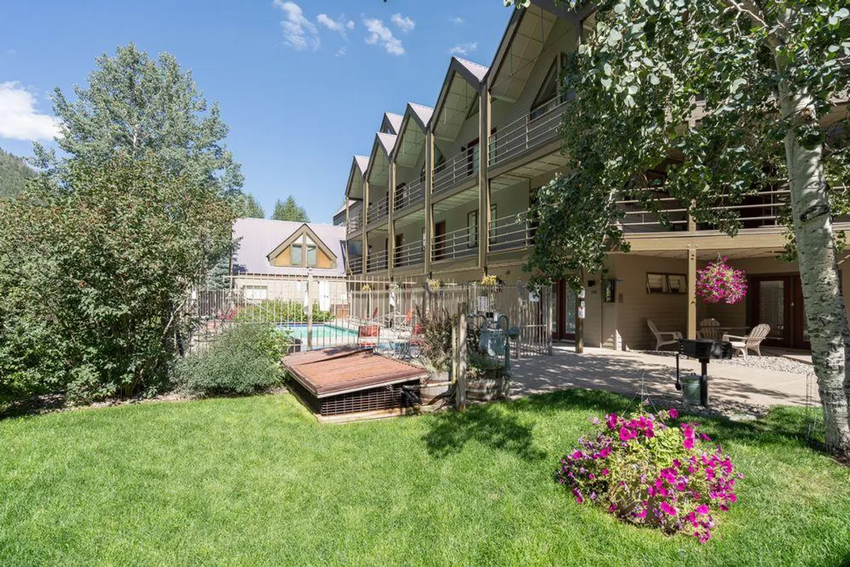 This image captures the resort's outdoor pool area, complete with flower beds and balconies overlooking the scene. The atmosphere is cheerful and social, suggesting a lively spot for swimming, sunbathing, and community gatherings in the summer months.